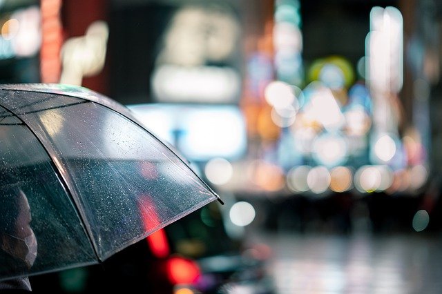 夜の街で傘をさしてる女性の画像