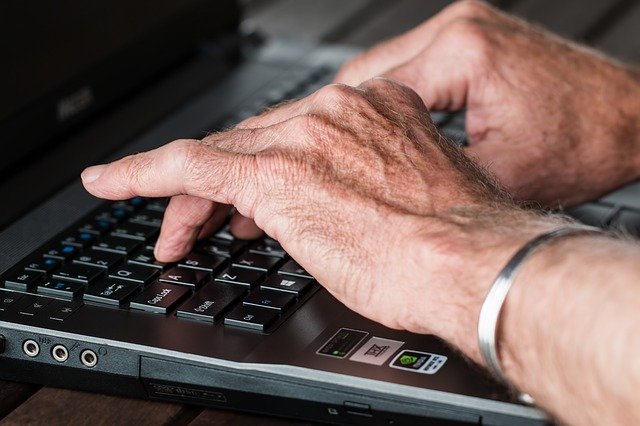 パソコンのキーボードで入力してる男の手の画像